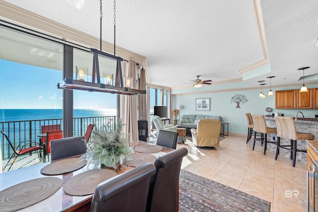 dining space with ornamental molding, a textured ceiling, ceiling fan, a water view, and light tile patterned flooring