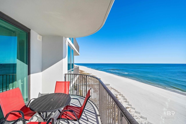 balcony featuring a view of the beach and a water view