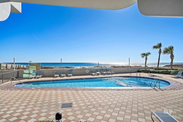 view of swimming pool featuring a water view and a patio