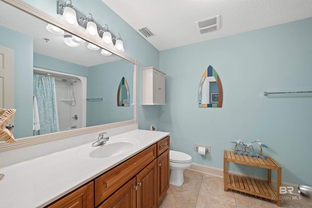 bathroom with tile patterned floors, vanity, a textured ceiling, and toilet