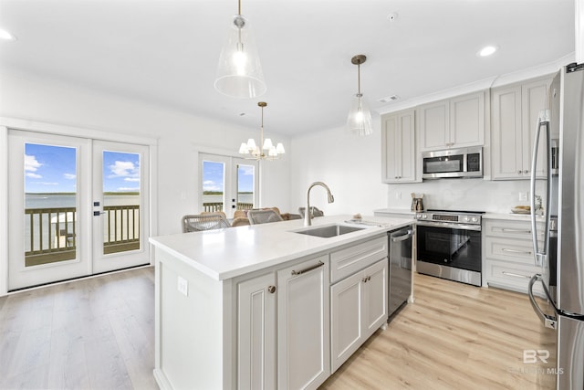 25995 W Perdido Ave, Orange Beach, AL 36561 - kitchen featuring appliances with stainless steel finishes, light wood-type flooring, a kitchen island with sink, light countertops, and a chandelier