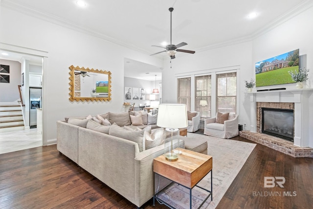 living room featuring a fireplace, dark hardwood / wood-style flooring, ceiling fan, and ornamental molding