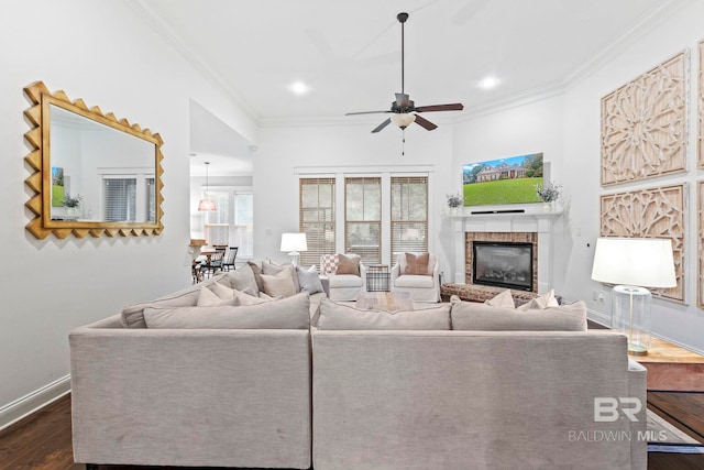 living room with ceiling fan, crown molding, dark wood-type flooring, and a brick fireplace