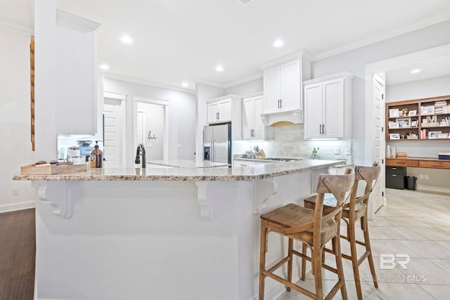 kitchen featuring backsplash, stainless steel fridge, light hardwood / wood-style floors, light stone counters, and white cabinetry