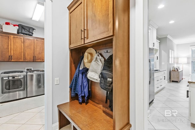 mudroom featuring washing machine and dryer, light tile patterned floors, and crown molding