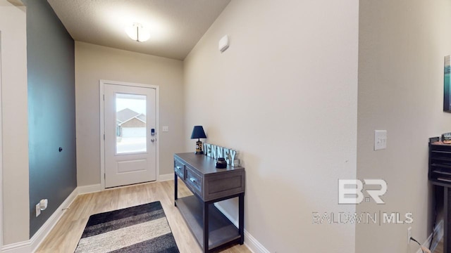 doorway featuring lofted ceiling and light hardwood / wood-style floors