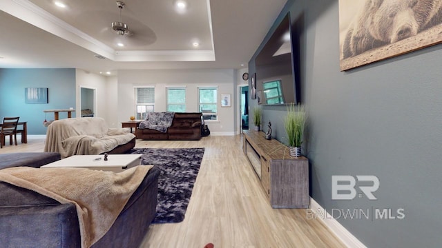 living room with crown molding, light hardwood / wood-style flooring, ceiling fan, and a raised ceiling