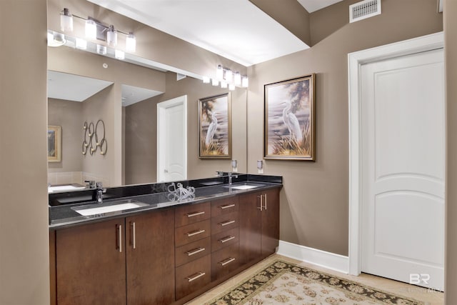 full bath with visible vents, a sink, baseboards, and double vanity