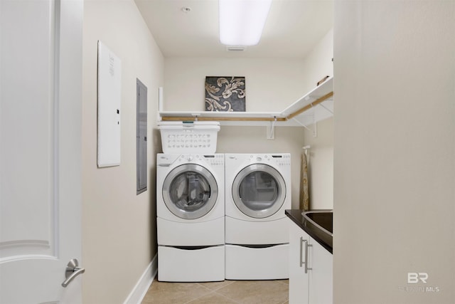 washroom with a sink, light tile patterned flooring, washing machine and dryer, and cabinet space