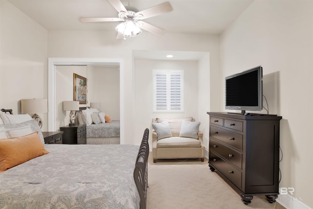 bedroom featuring light carpet, a ceiling fan, and a closet