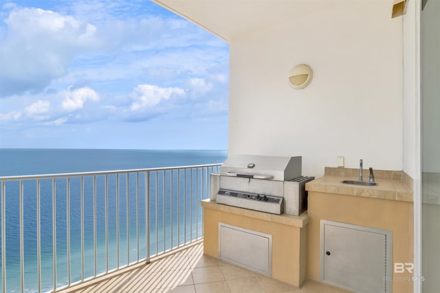 balcony with exterior kitchen, a water view, a sink, and grilling area