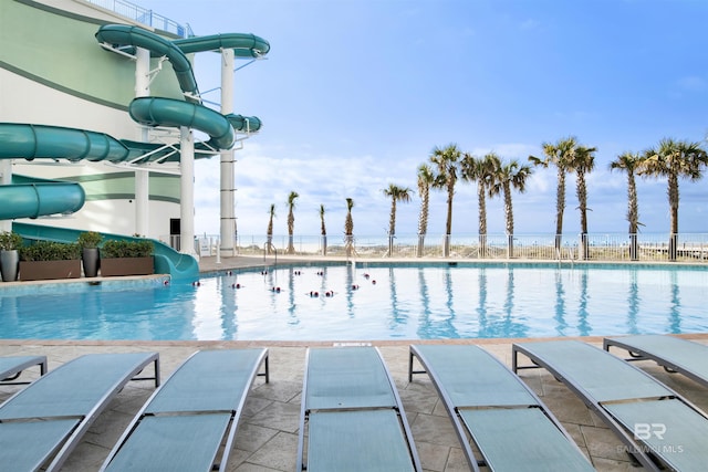 community pool featuring a patio area and a water slide