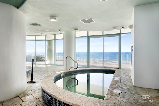 view of swimming pool with a water view and an indoor hot tub