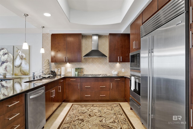 kitchen featuring built in appliances, light tile patterned floors, a sink, wall chimney range hood, and tasteful backsplash