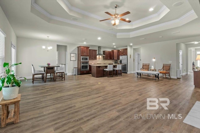 living room featuring crown molding, a tray ceiling, a chandelier, recessed lighting, and wood finished floors