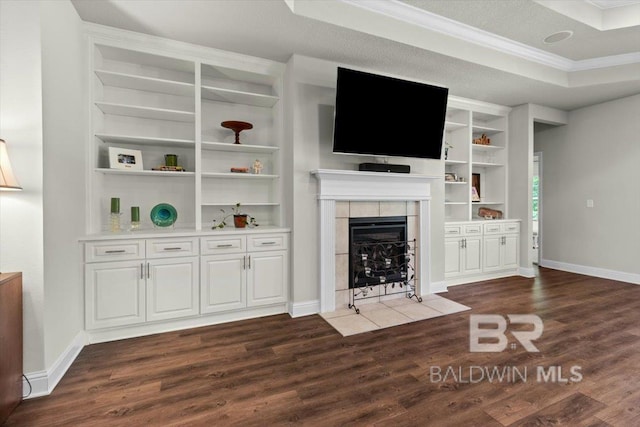 unfurnished living room featuring ornamental molding, dark wood-style floors, a fireplace, baseboards, and built in features