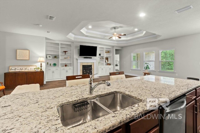 kitchen featuring a sink, open floor plan, dark wood-style flooring, ceiling fan, and a fireplace