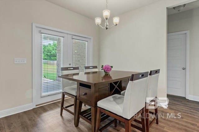 dining area featuring wood finished floors, a chandelier, and baseboards