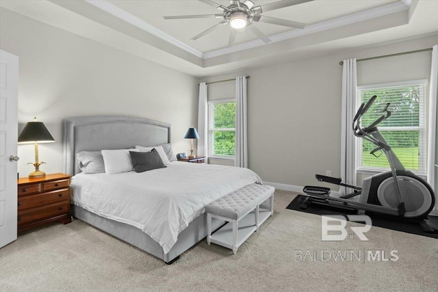 bedroom with carpet floors, crown molding, a tray ceiling, baseboards, and ceiling fan