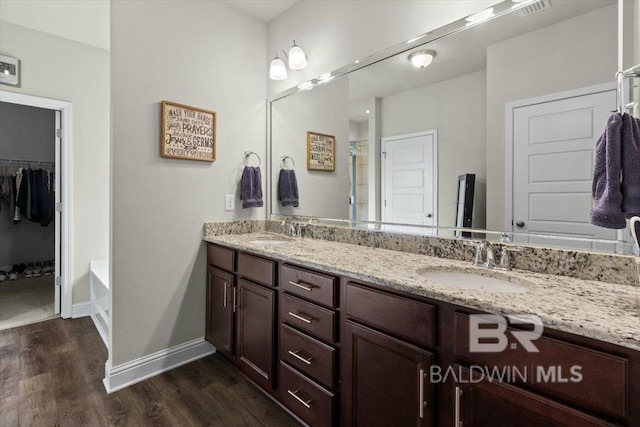 full bath with wood finished floors, double vanity, baseboards, and a shower