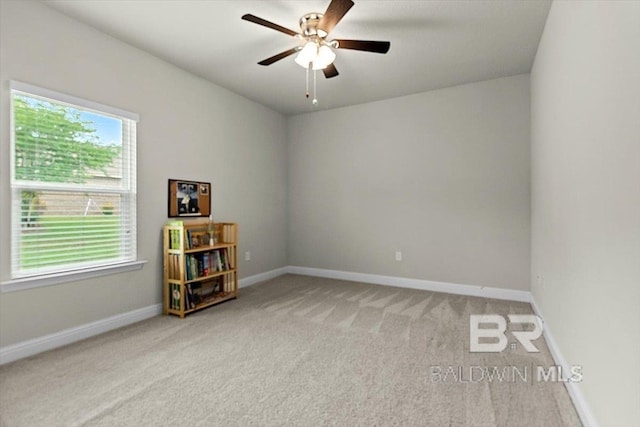 carpeted spare room with ceiling fan and baseboards
