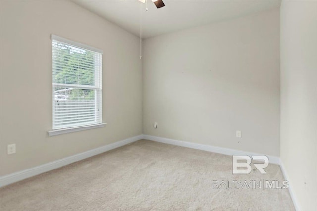 carpeted spare room with a ceiling fan and baseboards