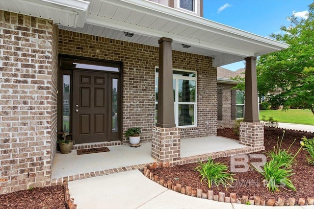 doorway to property featuring brick siding and a porch