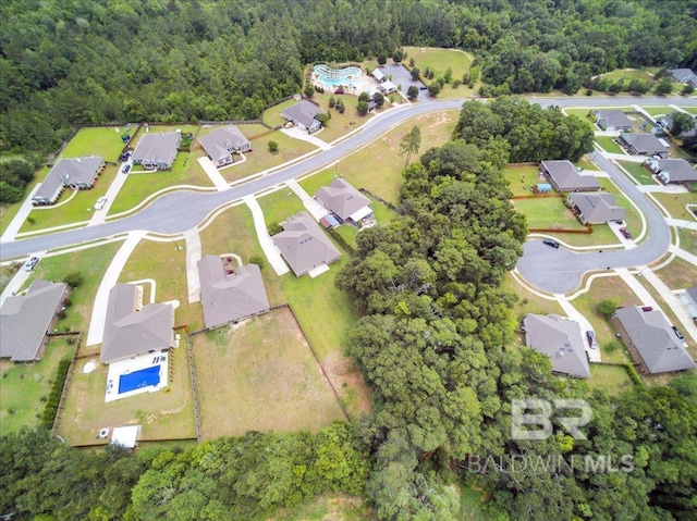 aerial view of property and surrounding area featuring nearby suburban area and a heavily wooded area