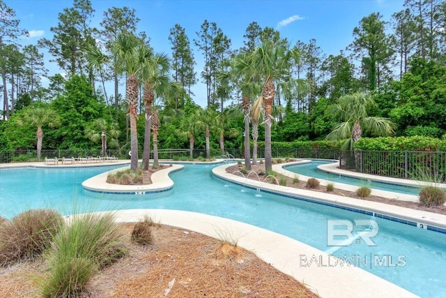 community pool featuring fence and view of wooded area