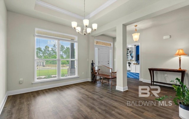 foyer featuring ornamental molding, wood finished floors, baseboards, a chandelier, and a tray ceiling