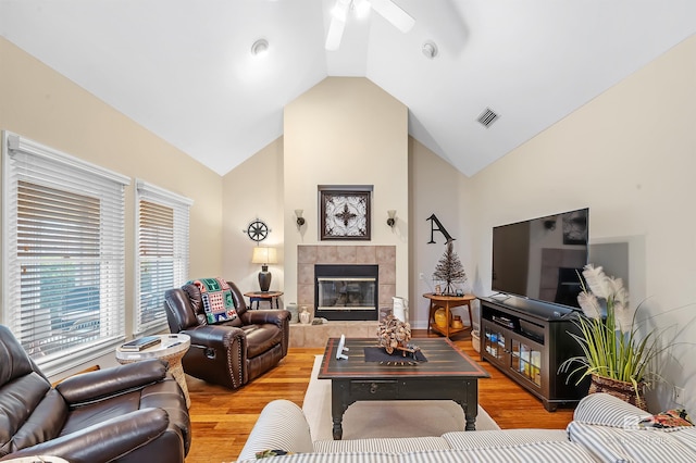 living room with lofted ceiling, ceiling fan, light wood-type flooring, and a tile fireplace