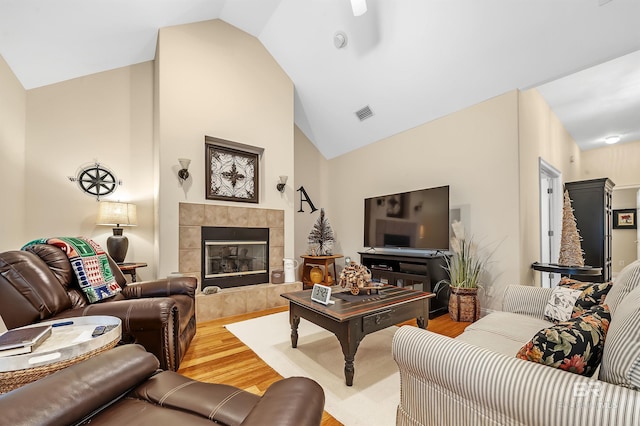 living room featuring a tile fireplace, hardwood / wood-style flooring, and lofted ceiling