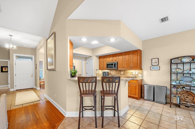 kitchen featuring a breakfast bar, light stone countertops, kitchen peninsula, and light tile patterned floors