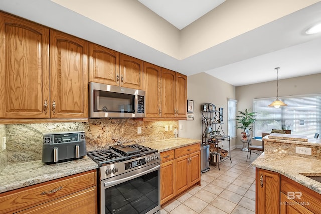 kitchen featuring light stone countertops, backsplash, stainless steel appliances, hanging light fixtures, and light tile patterned flooring