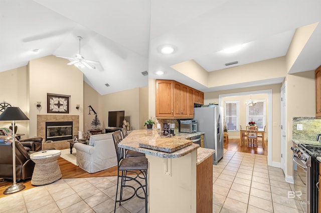 kitchen featuring a breakfast bar, light tile patterned flooring, kitchen peninsula, and stainless steel appliances