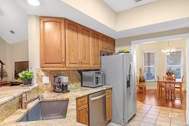 kitchen with light stone countertops, sink, a chandelier, light tile patterned flooring, and appliances with stainless steel finishes