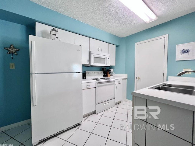 kitchen with a textured ceiling, white appliances, sink, light tile patterned floors, and white cabinetry