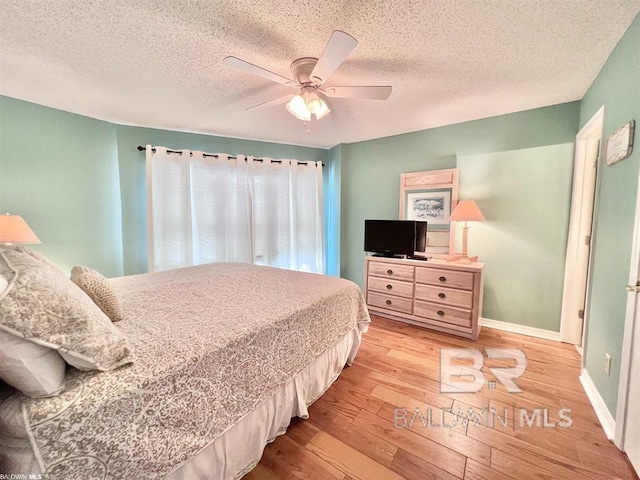 bedroom with ceiling fan, a textured ceiling, and light hardwood / wood-style flooring