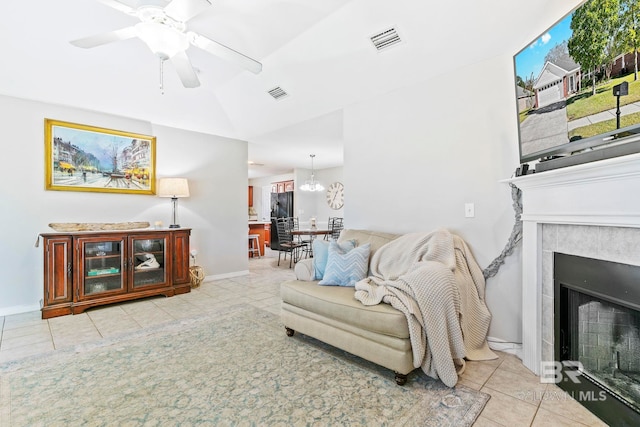 tiled living room featuring a fireplace and ceiling fan with notable chandelier