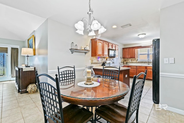 tiled dining area with sink, a chandelier, and lofted ceiling