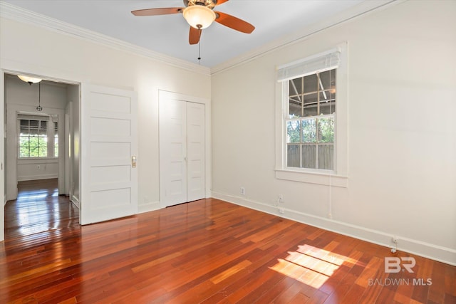 unfurnished bedroom featuring ceiling fan, wood-type flooring, crown molding, and multiple windows