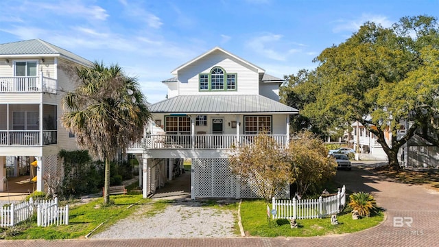 coastal home featuring fence, a porch, metal roof, a carport, and driveway