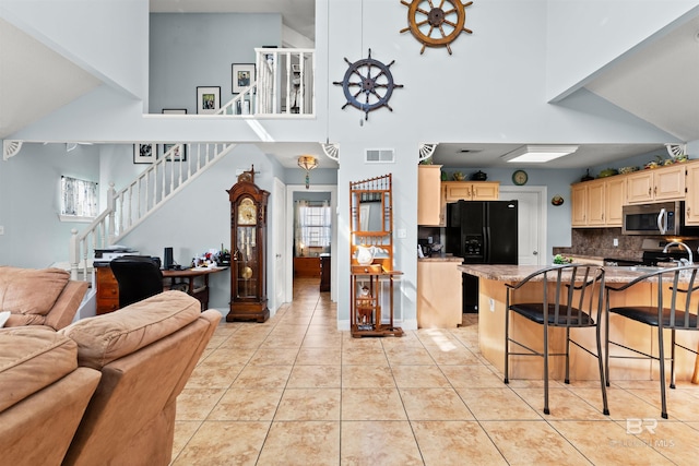 kitchen featuring visible vents, open floor plan, stainless steel appliances, a breakfast bar area, and light tile patterned floors