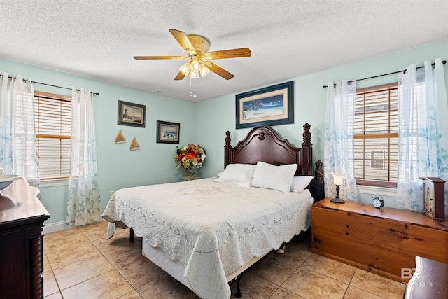 bedroom featuring light tile patterned flooring, a ceiling fan, and a textured ceiling