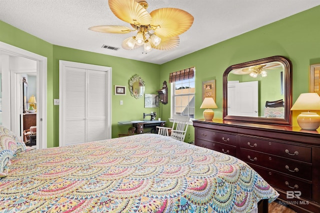 bedroom featuring a ceiling fan, visible vents, a closet, and a textured ceiling