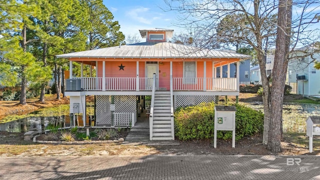 view of front of property with central air condition unit, a porch, metal roof, and stairs