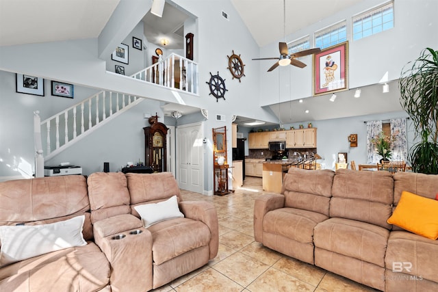 living room with stairway, light tile patterned floors, ceiling fan, vaulted ceiling, and a wealth of natural light