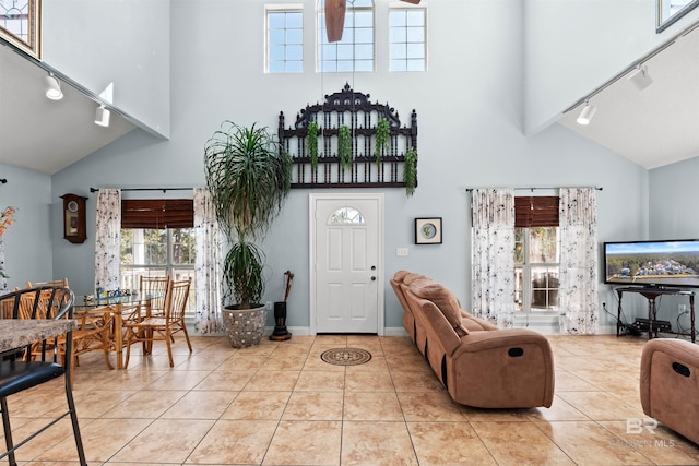 living room with rail lighting, light tile patterned floors, baseboards, and high vaulted ceiling