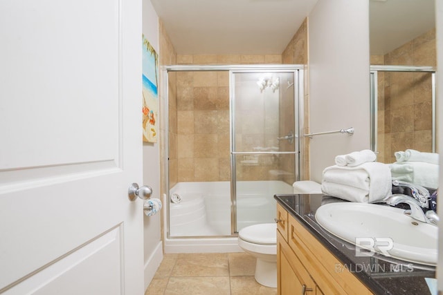 bathroom featuring toilet, vanity, a shower with shower door, and tile flooring