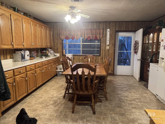 dining room with a ceiling fan, visible vents, and wooden walls